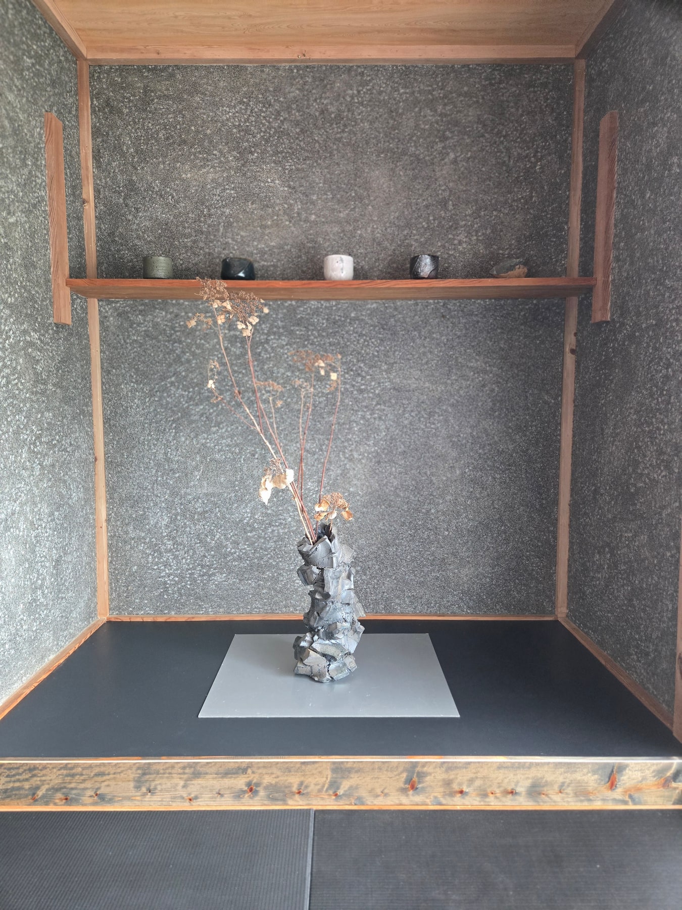 Sculptural ceramic vessel with dried flowers displayed in a tokonoma alcove