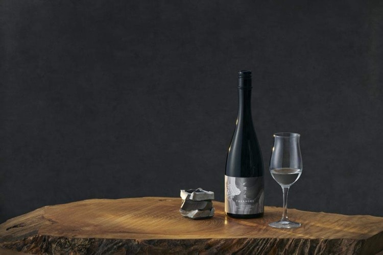 Ceramic sake cup with a sake bottle and glass on a natural-edge wooden table
